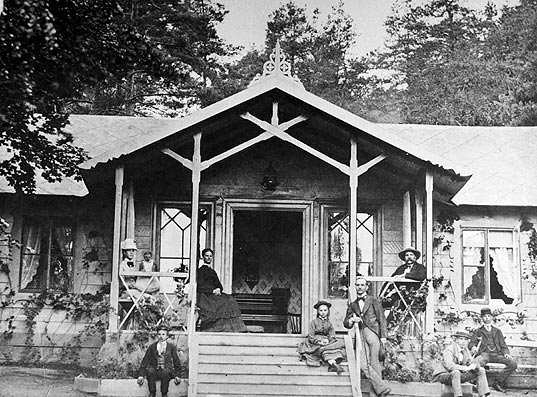 Sommarvilla vid huvudsta gård 1874. Öppen veranda med smäckra snickerier och trätrappa.